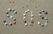SOS signal on the sand made from shells