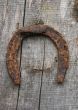  	Vintage horseshoe nailed at old wooden wall