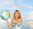 blonde in field on green grass holding globe in hand under blue