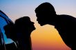 two Silhouettes of kissing people on sunset background