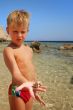  beach boy shows stone or seashell
