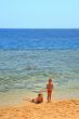 ma and son playing on beach on background blue sky