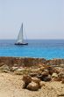 Stones on beach and yacht in sea