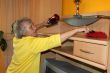 Old woman cleans a cupboard
