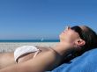 girl with sunglasses tanning on the beach