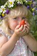 little girl in flowers wreat with strawberries in hands