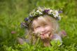 happy little girl in flowers wreath lying on green grass