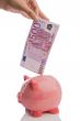Saving a note of five hundred euros in a piggy-bank