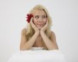 smiling face of model with red gerbera in hair
