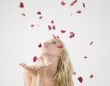 young caucasian lady blowing petals