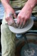Hands shaping clay on potter`s wheel