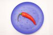 Pepper chile on violet plate with droplet of water