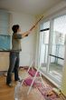 Young woman paints a wall in the kitchen