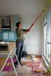 Young woman paints a wall in the kitchen