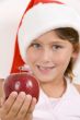 girl wearing christmas hat and holding an apple
