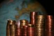 Stacks of Euro and Cent coins in front of a globe