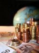Stacks of Euro and Cent coins in front of a globe