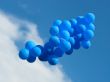 Sheaf of blue party balloons against the cloudy blue sky
