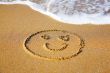 `Smile` drawing at sand, with sea wave