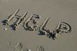 Help inscription on a sand beach