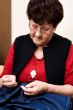 Grandmother sewing trousers on the couch