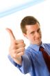 Young businessman showing thumb up. Sign `Yes`