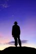 Silhouette of lone man on mountain in twilight