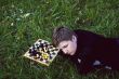 Woman lying in the grass near the chess board