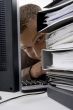 young man looking between the files and computer