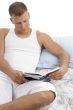 man lying on bed and reading book