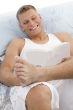 smiling handsome male reading book in bed
