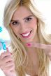 front view of smiling woman pointing at toothbrush