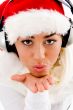 woman wearing christmas hat giving blowing a kiss