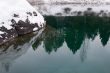 Big stone covered a snow in nonfreezing blue lake