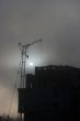 Gray sunset sky with lifting construction cranes