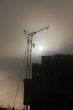 Gray sunset sky with lifting construction cranes