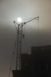 Gray sunset sky with lifting construction cranes