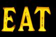 Neon sign with the word `Eat` over black