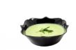 Green soup on the black plate on whote background