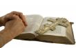 Hands closed in prayer and cross on an open bible