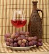 Carafe, grape and goblet on mat
