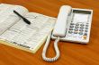 White telephone on wooden desk.