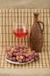 Ceramic bottle, grape and goblet on mat