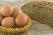 Many fresh rural eggs lying in a wattled small basket near to fr