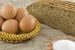 Many fresh rural eggs lying in a wattled small basket near to fr