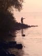 Silhouette of alone fisher near sunset river