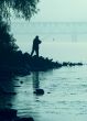 Silhouette of alone fisher near sunset river