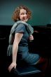 young girl sitting near piano in dress smiling