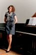 young lady in dress standing near piano