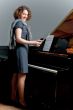 pretty young girl standing near piano smiling